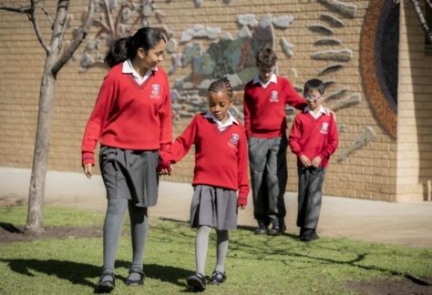 Older primary school students with young primary students supporting eachother outside